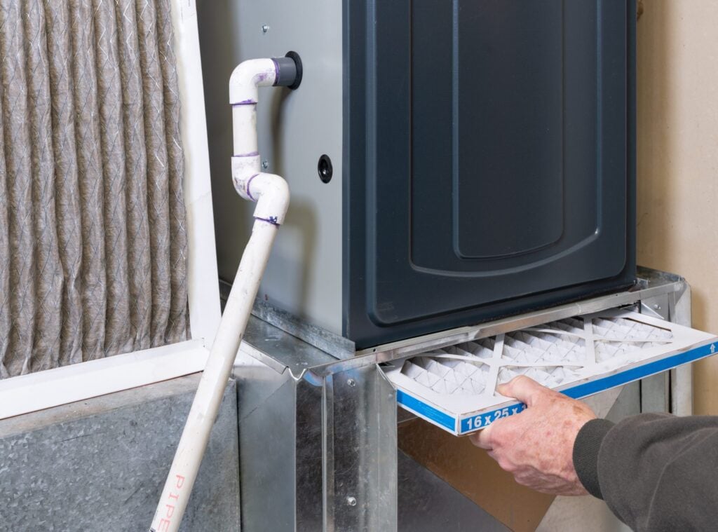 A person is replacing an old HVAC air filter with a new one